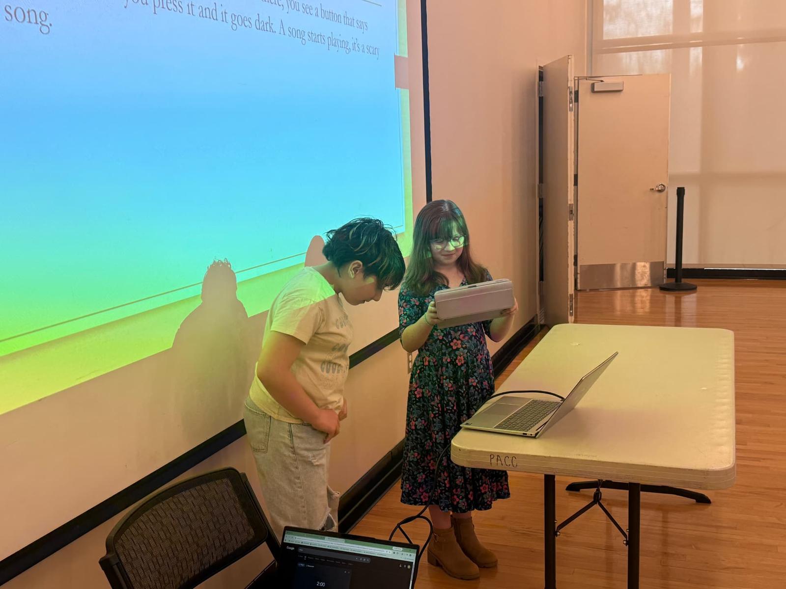 Two students read their game story aloud in front of the projector