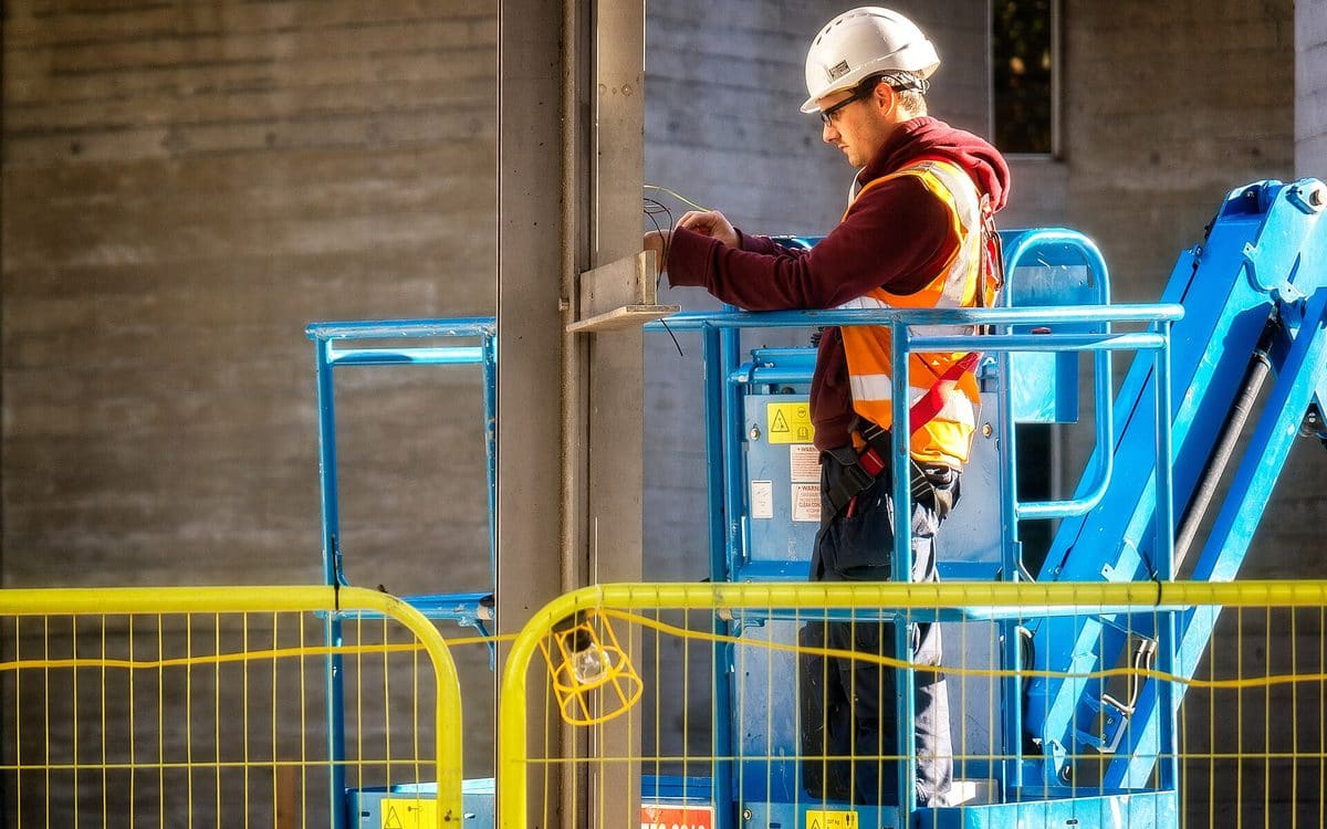 Electrician in a hard hat wiring a panel inside a building under construction