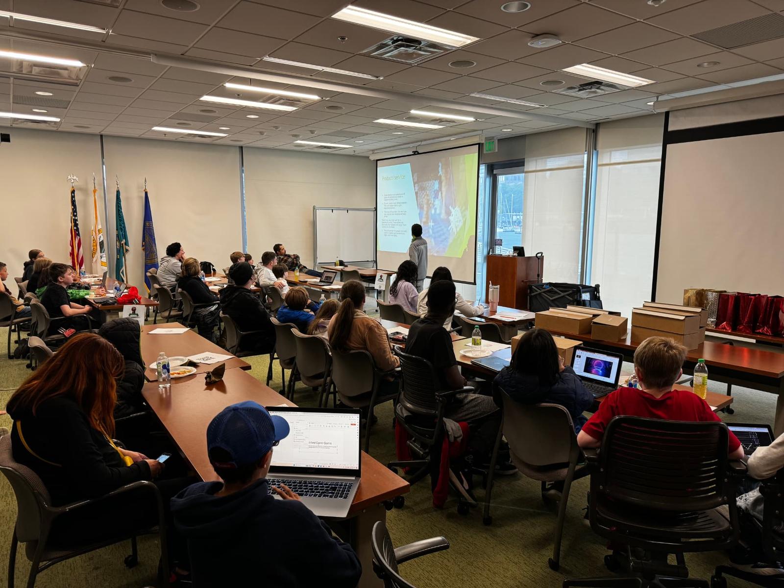 A student presents a product and service slide to a full room