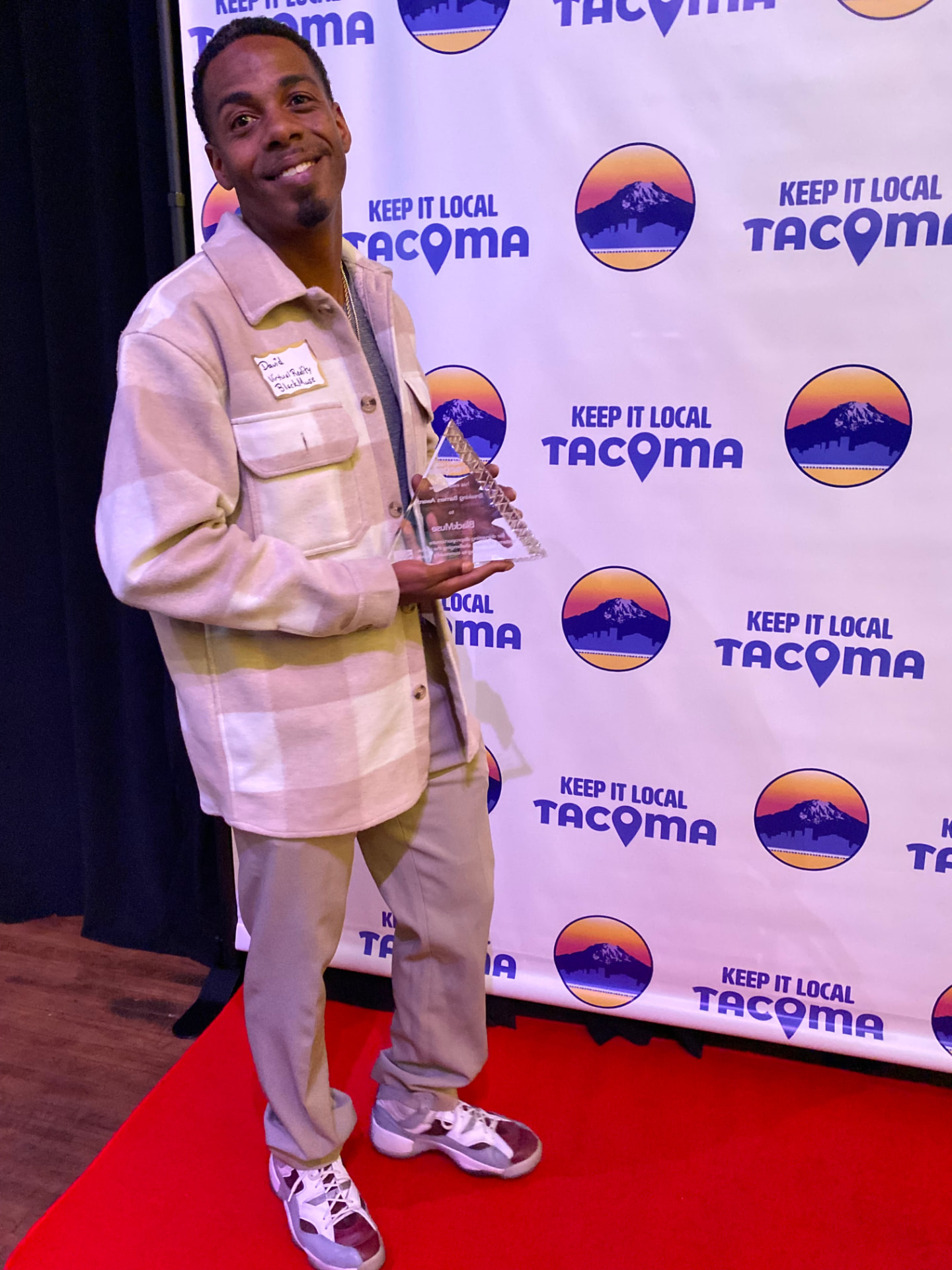 David Robicheaux holding the Breaking Barriers Award at a Keep It Local Tacoma event